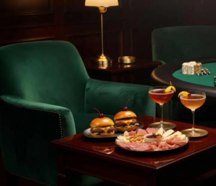 Gourmet bar snacks and cocktails arranged beside a poker table in a lounge